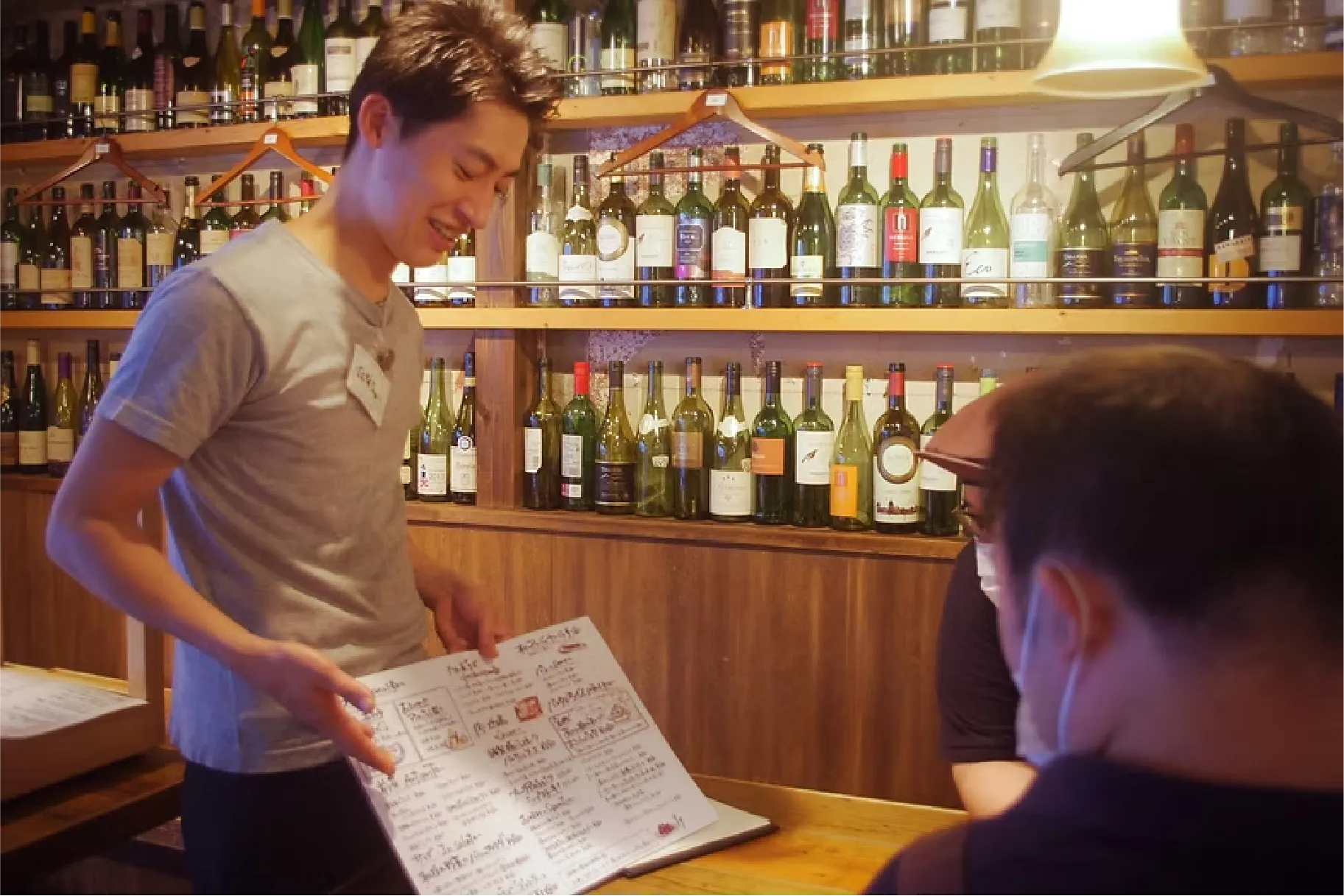 スタッフがメニューを手に取り、お客様に丁寧に説明している接客風景