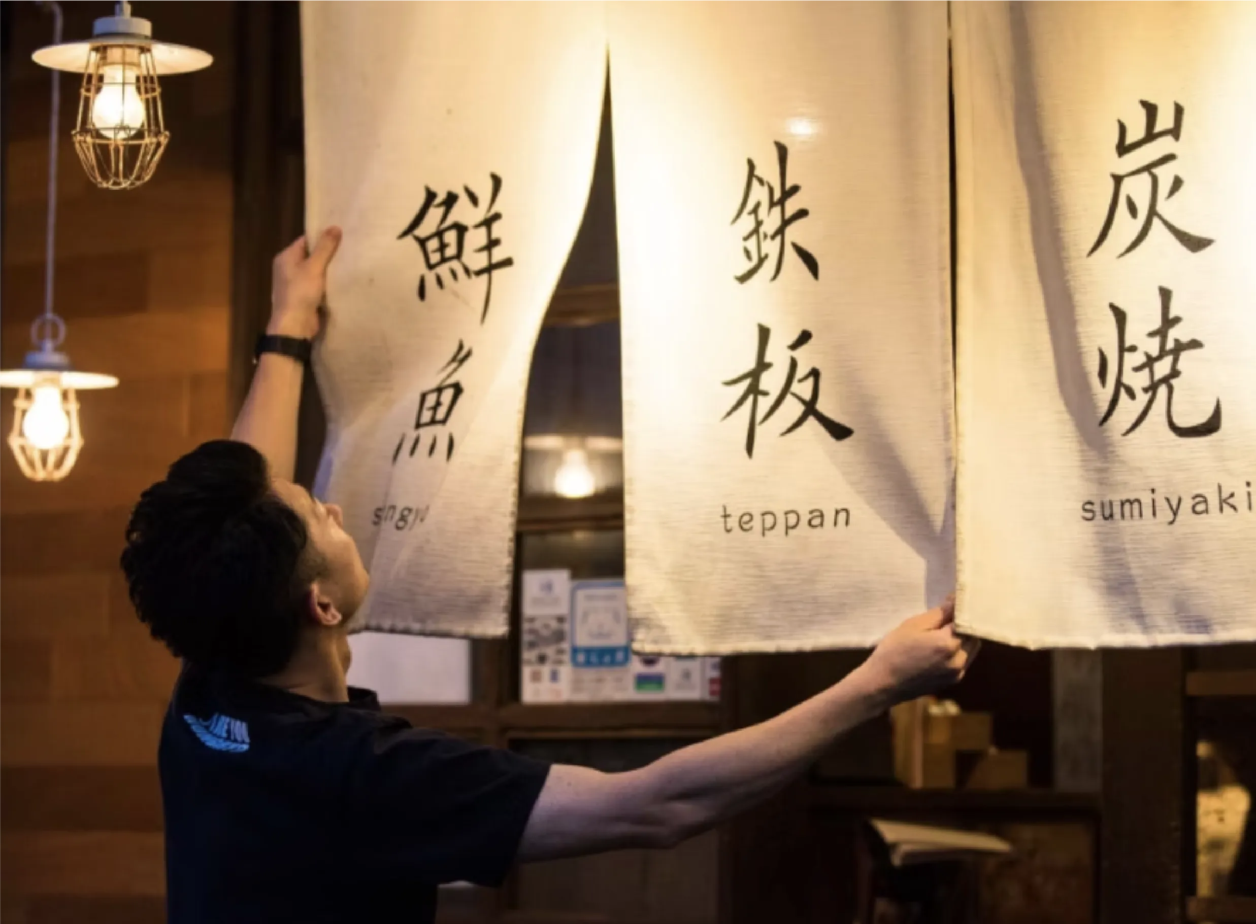 スタッフが開店に向けて暖簾をかける様子